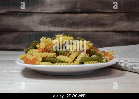 Schöne mehrfarbige Pasta auf einem weißen Teller. Pasta als Hintergrund Stockfoto