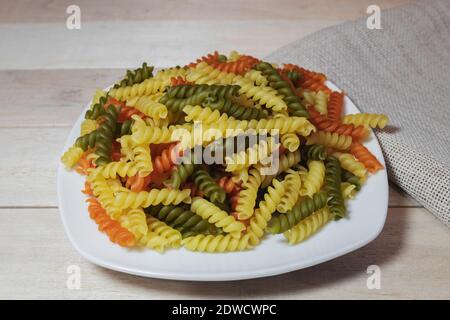 Schöne mehrfarbige Pasta auf einem weißen Teller. Pasta als Hintergrund Stockfoto