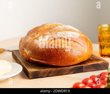 Ganzer Laib frisch gebackenes Weizenbrot auf Holz Brett auf heimischen Küchentisch Stockfoto