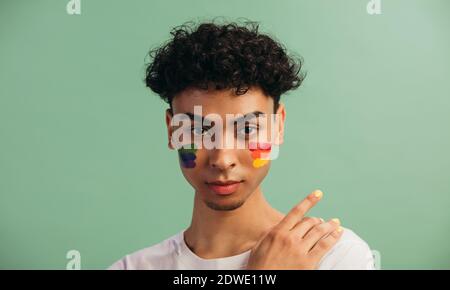 Porträt eines jungen Mannes mit LGBT-Flagge auf seinen Wangen. Thema der Gleichheit und der Freiheit der Wahl. Stockfoto