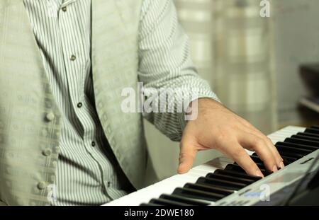 Die Hände des Musikers auf dem Klaviertastatur während des Spielens. Ein Mann spielt zu Hause einen Synthesizer. Hintergrund mit Platz für Text Stockfoto