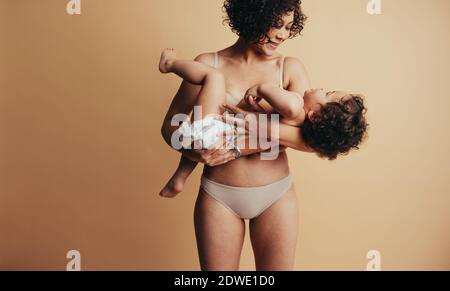 Frau, die ihr Kind in den Armen trägt. Liebevolle Mutter und Baby. Stockfoto