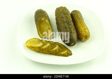 Gurken aus der Dose auf einem Teller auf weißem Hintergrund. Eingelegte und knusprige Gurken, leckere eingelegte Gurken Stockfoto