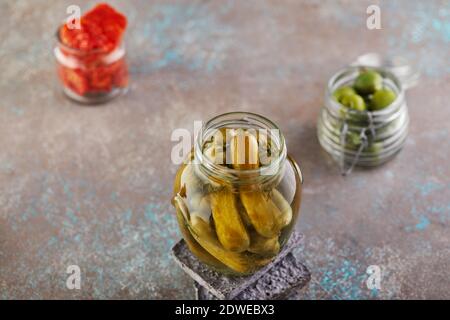 Fermentierte vegetarische Konserven Konzept. Eingelegte Gurken, Oliven, getrocknete Tomaten in Gläsern. Das Konzept der Konserven Stockfoto