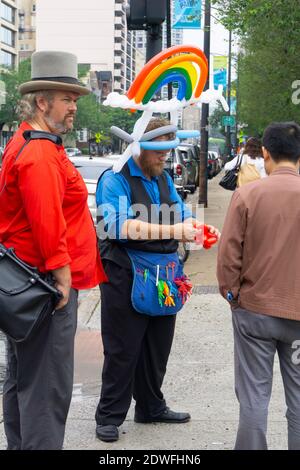 Chicago USA August 30 2015; Street Performer Formen aus farbigen Luftballons, um Passanten mit einem Regenbogen auf dem Kopf und Schürze mit s zu unterhalten Stockfoto