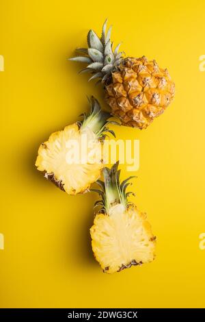 Reife Baby Ananas. Halbierte Mini-Ananas auf gelbem Hintergrund. Draufsicht. Stockfoto