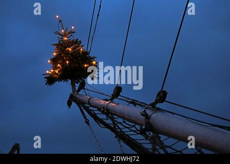 Rostock, Deutschland. Dezember 2020. Zu Weihnachten mit einem Weihnachtsbaum auf dem Jib-Boom geschmückt, liegt das traditionelle Segelschiff 'Santa Barbara Anna' im Stadthafen. Urlauber und Touristen sind an der Ostsee nicht mehr erlaubt seit Beginn der zweiten Sperre feiern die Hanseaten Weihnachten und Silvester zu Hause und untereinander. Quelle: Bernd Wüstneck/dpa-Zentralbild/ZB/dpa/Alamy Live News Stockfoto