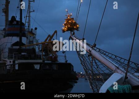 Rostock, Deutschland. Dezember 2020. Zu Weihnachten mit einem Weihnachtsbaum auf dem Jib-Boom geschmückt, liegt das traditionelle Segelschiff 'Santa Barbara Anna' im Stadthafen. Urlauber und Touristen sind an der Ostsee nicht mehr erlaubt seit Beginn der zweiten Sperre feiern die Hanseaten Weihnachten und Silvester zu Hause und untereinander. Quelle: Bernd Wüstneck/dpa-Zentralbild/ZB/dpa/Alamy Live News Stockfoto