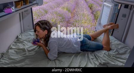 Lavendelblüte, Frau riecht Lavendelaroma sitzend in einem Wohnmobil, Stockfoto