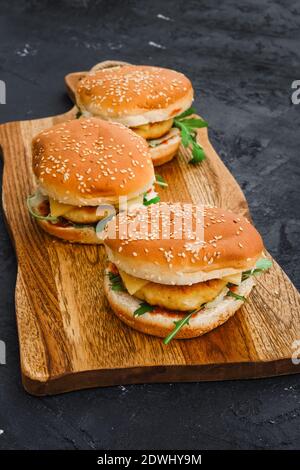 Hausgemachter Burger mit Hähnchenschnitzel auf langer Holzplatte Stockfoto