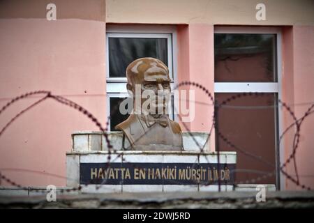 Eine Bronzebüste des türkischen Gründers Mustafa Kemal Atatürk hinter Stacheldraht vor der Wand eines Schulgebäudes. Symbol der Unterdrückung von Kem Stockfoto