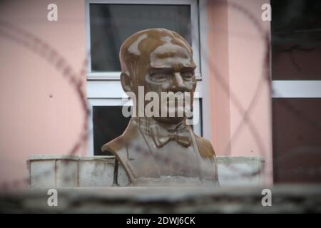 Eine Bronzebüste des türkischen Gründers Mustafa Kemal Atatürk hinter Stacheldraht vor der Wand eines Schulgebäudes. Symbol der Unterdrückung von Kem Stockfoto