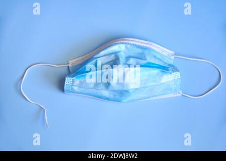 Zerrissene medizinische Maske auf blauem Hintergrund, das Konzept der Viruserkrankungen, Coronavirus. Stockfoto