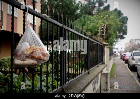 An einem Zaun in Istanbul hängt eine Plastiktüte mit abgestandenem Brot. Das abgestandene Brot soll für arme Leute sein, aber es geht meist schimmelig. Stockfoto