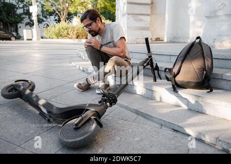 Junger Mann Unfall Mit Einem Elektroroller Auf Der Straße. Ein Mann fiel von einem Roller auf einer Stadtstraße. Stockfoto