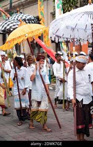 Galungan Urlaub. Festliche Prozession der Männer mit Regenschirmen in den Händen. Bali, Indonesien. 26.12.2018. Stockfoto