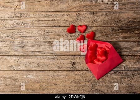 Herzen, die aus einem roten Umschlag auf einem Holztisch kommen Stockfoto