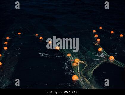 Trawlernetze schwimmen nachts vom Heck des Bootes. Stockfoto