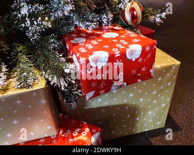 Weihnachtsgeschenke eingewickelt in rot und Gold Papier unter einem Weihnachtsbaum, der von Vater Santa Claus zu verlassen war Am zweiten Weihnachtsfeiertag geöffnet sein Stockfoto