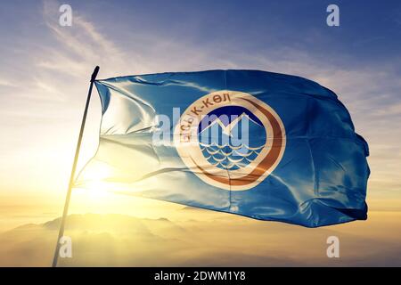 Issyk-Kul Region Oblast Kirgisistan Flagge winkt auf der Spitze nebel bei sonnenaufgang Stockfoto