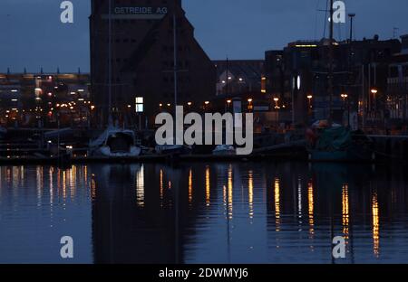 Rostock, Deutschland. Dezember 2020. Im Stadthafen werden am frühen Morgen Lichter im Wasser reflektiert. Urlauber und Touristen sind an der Ostsee nicht erlaubt seit Beginn der zweiten Sperre Anfang November feiern die Hanseaten Weihnachten und Silvester zu Hause und untereinander. Quelle: Bernd Wüstneck/dpa-Zentralbild/ZB/dpa/Alamy Live News Stockfoto