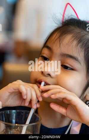 Asiatische Kind niedlich oder Kind Mädchen Trinkwasser oder Soja Milch Getränk in Flasche für Rohr oder Stroh und Essen Snack oder Dessert Stockfoto