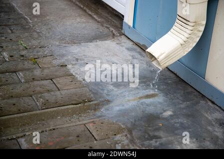 Regenwasser fließt über einen Abfluss vom Dach des Gebäudes. Entfernung von Regenwasser. Downpipe Weiß Stockfoto