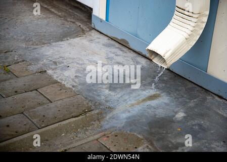 Regenwasser fließt über einen Abfluss vom Dach des Gebäudes. Entfernung von Regenwasser. Downpipe Weiß Stockfoto