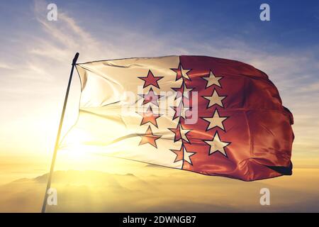 Walliser Kanton Schweiz Flagge winkt auf dem oberen Sonnenaufgang Nebelnebel Stockfoto