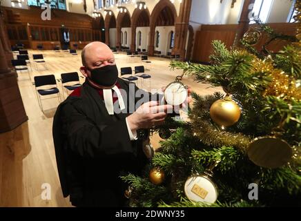 Der sehr Rev Dr. Derek Browning ehemaliger Moderator der General Assembly Church of Scotland mit dem Weihnachtsbaum in der Morningside Parish Church, Edinburgh, als er Vorbereitungen für die Gläubigen vor dem Weihnachtsgottesdienst macht. Stockfoto