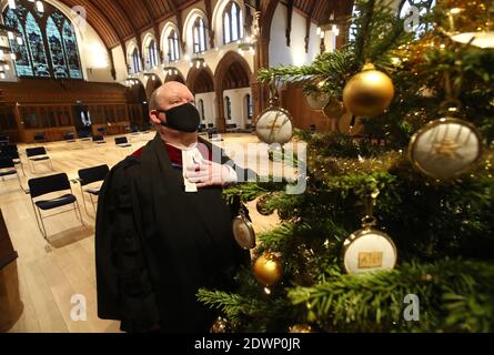 Der sehr Rev Dr. Derek Browning ehemaliger Moderator der General Assembly Church of Scotland mit dem Weihnachtsbaum in der Morningside Parish Church, Edinburgh, als er Vorbereitungen für die Gläubigen vor dem Weihnachtsgottesdienst macht. Stockfoto