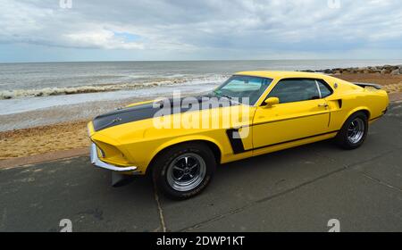 Classic Yellow Ford Mustang auf Strandpromenade Strand und Meer im Hintergrund geparkt. Stockfoto