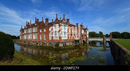 Helmingham Hall mit Graben Brücke und Reflexionen. Stockfoto