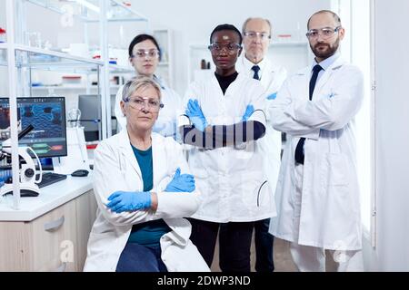 Team von professionellen Wissenschaftlern stehen zusammen in Forschungslabor Blick auf Kamera posiert mit Armen gekreuzt. Afrikanischer Gesundheitswissenschaftler im biochemischen Labor, der sterile Geräte trägt. Stockfoto