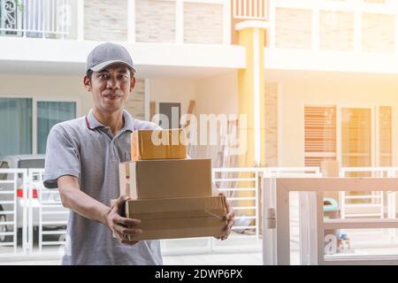 Zusteller in grauer Uniform stehen mit Boxen und lächeln an der Vorderseite des Kunden.-Lieferung und Kurierservice Konzepte. Stockfoto