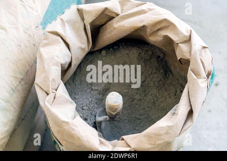 Nahaufnahme Kelle und Zementpulver in Papiertüte. Stockfoto