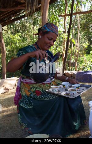 Lalibela-Ethiopia: 12. April 2019: Äthiopische Frau in gießt Kaffee aus Tonglas Kaffeekanne als Jebena bekannt Stockfoto