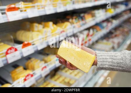 Frauenhand mit Käse im Supermarkt. Stockfoto