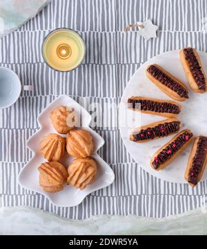 Kreative Xmas Tischeinstellung mit Eclirs, Braukuchen. Teller mit Kuchen in Form von Weihnachtsbaum. Süßigkeiten in herzförmiger Schüssel. Tannenzweige mit Tanne Stockfoto