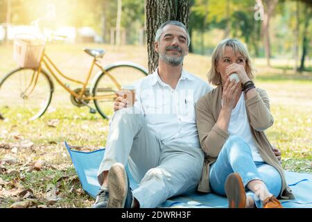 Glückliches Liebespaar, das Zeit im Park verbringt, Kaffee trinkt und sich entspannt Stockfoto