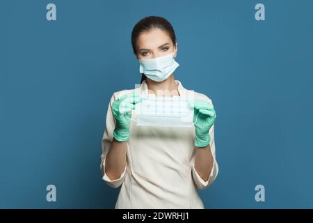 Arzt Frau oder Facharzt tragen professionelle medizinische Uniform und Schutzmaske mit Schutzmaske auf blau Stockfoto