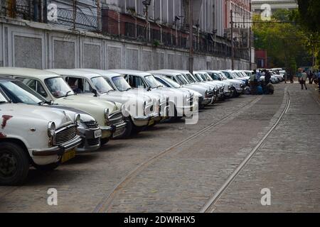 Kalkutta, Indien - März 2014: Reihe alter alter alter alter weißer Ambassador-Taxis entlang der Straßenbahnschienen in Kalkutta. Oldtimer in Reihe. Stockfoto