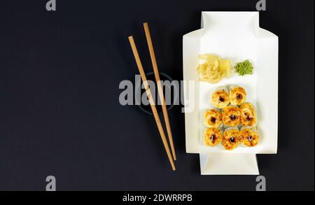 Heiß gebackene Sushi-Rollen in Öko-Einweg-Box Draufsicht auf dunklem Hintergrund. Lieferung Service consept Stockfoto