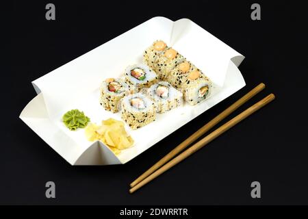 Japanische Sushi-Rollen in weißem Öko-Papier Einweg-Box auf Nahaufnahme mit dunklem Hintergrund Stockfoto
