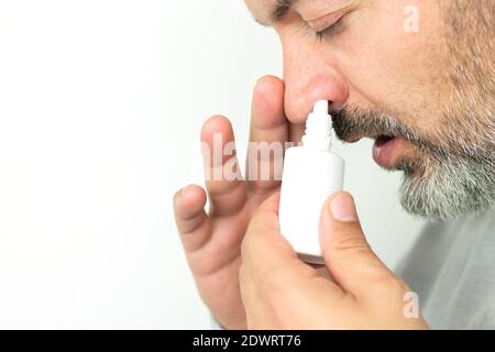 Bärtiger älterer Mann, der Spray für die laufende Nase anwendet. Behandlung von Erkältungen und Grippe-Konzept Stockfoto