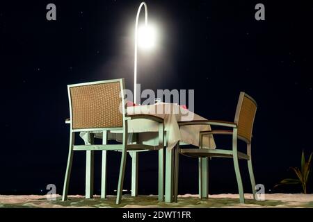 Esstisch am Sandstrand in der Nacht, romantisches Abendessen im Luxus-Resort, Malediven. Stockfoto