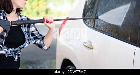 Frau mit Druckwasser auf dem Fenster bei der Autowäsche Stockfoto