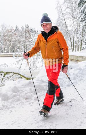 Älterer Mann, der im Winter beim nordic Walking Spaß hat Stockfoto