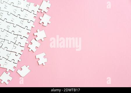 Weiße Puzzle-Stücke in der Ecke auf rosa Hintergrund mit Copyspace Stockfoto