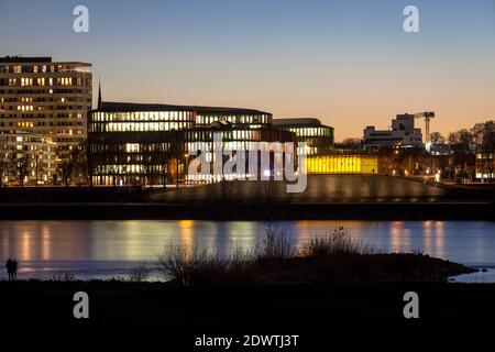 Blick über den Rhein zum Bürogebäude Köln Oval Büros und dem gelb beleuchteten Hochwasserpumpwerk im Stadtteil Bayenthal, Colo Stockfoto